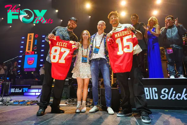 Travis Kelce (L) and Patrick Mahomes (R) pose onstage with donors Katherine Schell and Brian Schell