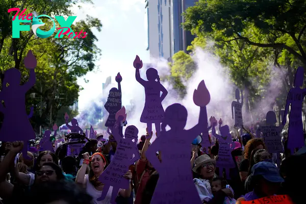 Women, many holding up purple silhouette cutouts that depict the anti-monument "Mujeres que luchan" or women who fight, march to the Zocalo to mark International Day for the Elimination of Violence against Women, in Mexico City, Nov. 25, 2023.