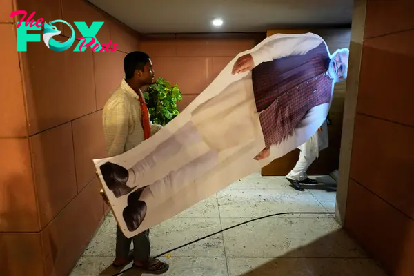 Workers carry a large cutout portrait of Modi at the party headquarters in New Delhi, June 4.