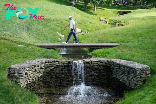 Scottie Scheffler walks across a creek on the 17th hole during the second round of the Memorial Tournament at Muirfield Village Golf Club.