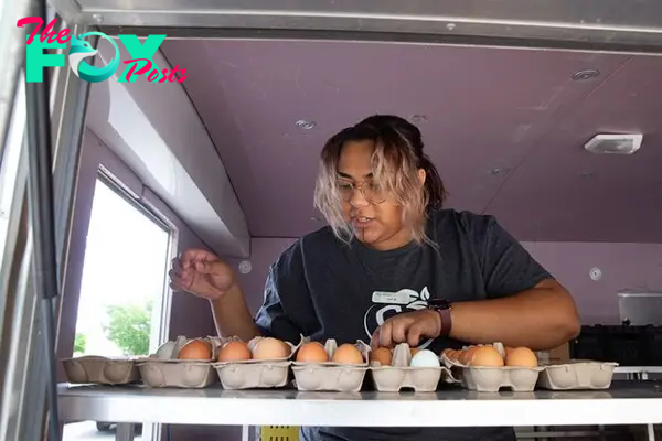 A woman places eggs in cartons inside a fresh-food truck
