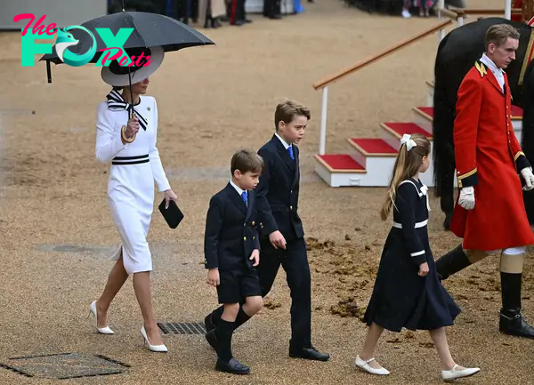Britain's Catherine, Princess of Wales, shelters from the rain with an umbrella as she walks with her children Britain's Prince George of Wales (C), Britain's Princess Charlotte of Wales (R) and Britain's Prince Louis of Wales back to the Glass State Coach at Horse Guards Parade during the King's Birthday Parade "Trooping the Colour" in London on June 15, 2024. 