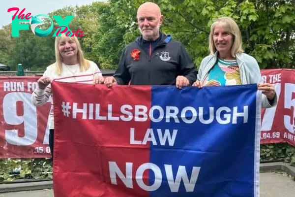 Margaret Aspinall- mother of James Aspinall, Steve Kelly - brother of Michael Kelly, Sue Roberts - sister of Graham Roberts hold Hillsborough Law Now banner - May 18, 2023