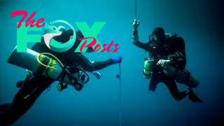 Underwater view of two technical divers using rebreathers device to locate shipwreck.