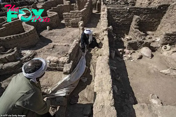 A picture taken on April 10, 2021, shows workers at the archaeological site of a 3000 year old city, dubbed The Rise of Aten, dating to the reign of Amenhotep III, uncovered by the Egyptian mission near Luxor