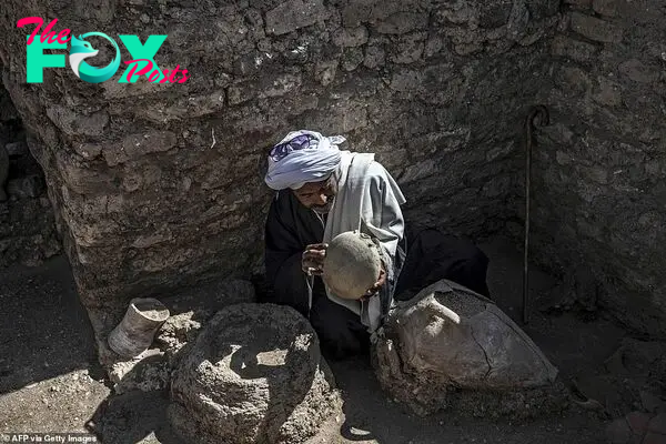 A picture taken on April 10, 2021, shows a worker inspecting an artifact at the archaeological site of a 3000 year old city, dubbed The Rise of Aten, dating to the reign of Amenhotep III, uncovered by the Egyptian mission near Luxor. - Archaeologists have uncovered the remains of an ancient city in the desert outside Luxor that they say is the 'largest' ever found in Egypt and dates back to a golden age of the pharaohs 3,000 years ago. Famed Egyptologist Zahi Hawass announced the discovery of the 'lost golden city', saying the site was uncovered near Luxor, home of the legendary Valley of the Kings