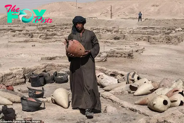 A worker walks with a pot recovered from the city among piles of other ancient artefacts which will be studied further by scientists