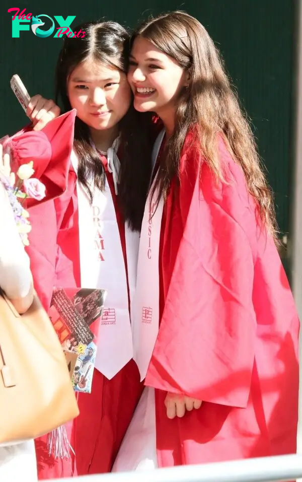 Suri Cruise smiles with a friend after she graduates high school