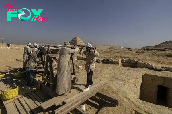 Egyptian antiquities workers dig at the Saqqara archaeological site.