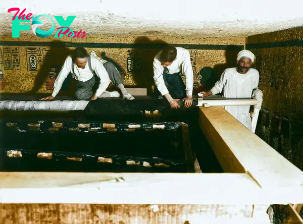 Carter, Mace and an Egyptian worker carefully roll up the linen pall covering the second shrine, 30th October 1923. Image courtesy of Griffith Institute, University of Oxford, colourised by Dynamichrome