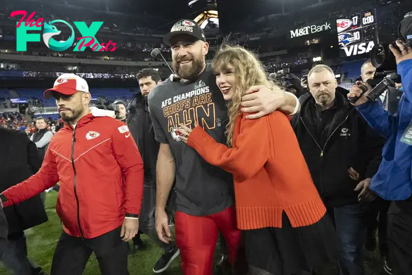 Travis Kelce and Taylor Swift walk together after an AFC Championship NFL football game.