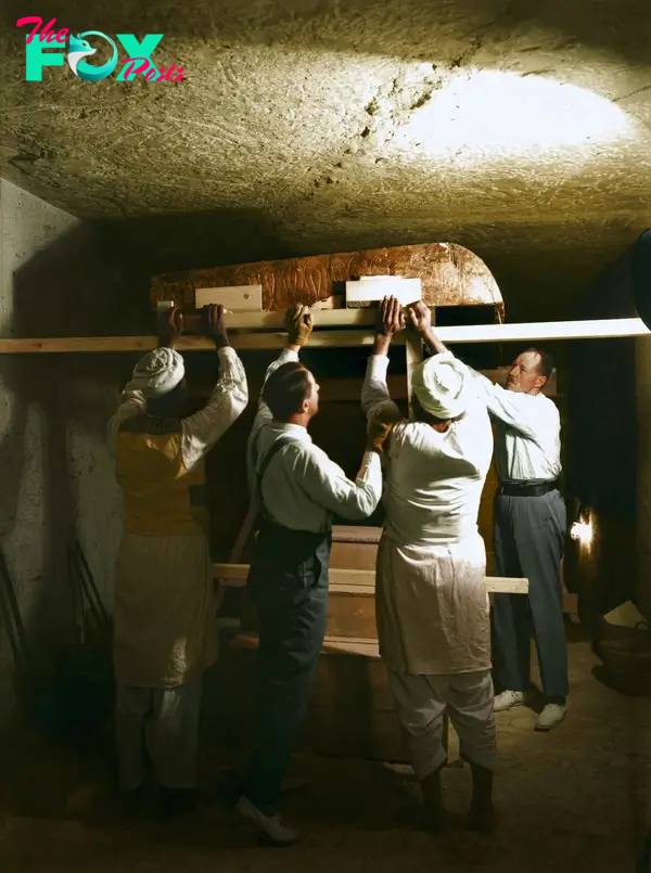 Carter, Callender and two Egyptian workers carefully dismantle one of the golden shrines within the burial chamber, December 1923. Image courtesy of Griffith Institute, University of Oxford, colourised by Dynamichrome