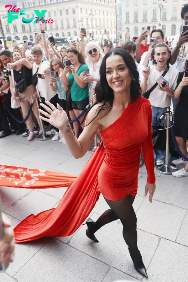 Katy Perry wearing a red dress with "Woman's World" lyrics on the train