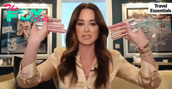 Kyle RIchards holding up lip gloss in both hands