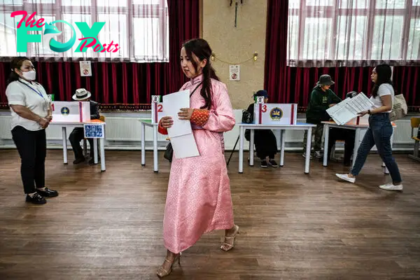 A woman dressed in traditional deel clothing votes in the Mongolian parliamentary elections at a polling station in Ulaanbaatar, Mongolia on June 28, 2024.
