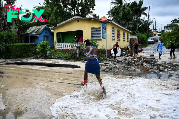 A woman runs as water from the sea floods a street after the passage of Hurricane Beryl in the parish of Saint James, Barbados, near Bridgetown on July 1, 2024.