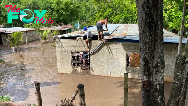 Residents fix the roof of their flooded house after a river swelled due to heavy rains following the passage of Hurricane Beryl on the road from Cumana to Cumanacoa, Sucre State, Venezuela, on July 2, 2024.