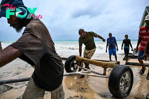 Residents clear boat from the street as it gets flooded after the hurricane Beryl passes in the parish of Saint James, Barbados, near to Bridgetown, Barbados on July 1, 2024.