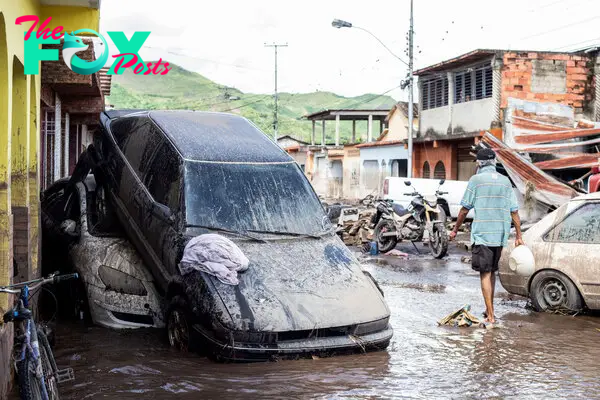 A man walks near damaged vehicles after devastating floods swept through the town after Hurricane Beryl passed off the Venezuelan coast, in Cumanacoa, Venezuela, on July 2, 2024.