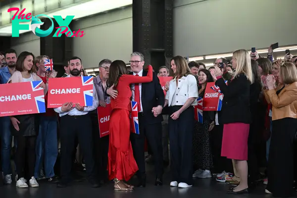 Britain's Labour Party leader Keir Starmer, center, is hugged as he arrives with his wife Victoria to deliver a speech during a victory rally at the Tate Modern in London early on July 5, 2024.