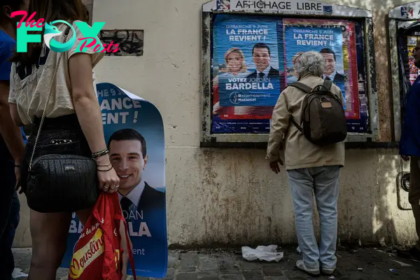 France's far-right Rassemblement National (RN) party volunteers paste campaign posters of party President and lead European Parliament election candidate Jordan Bardella in Lyon on May 6, 2024.