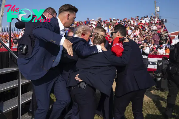 Republican presidential candidate former President Donald Trump is helped off stage by U.S. Secret Service agents.