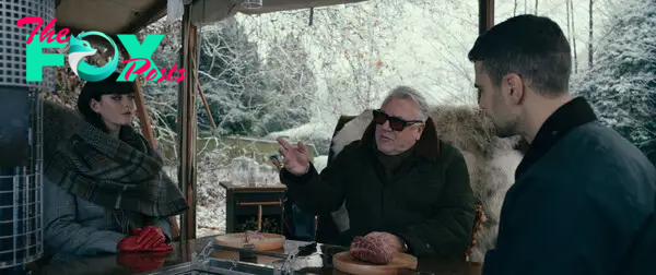 Kaya Scodelario, Ray Winstone, and Theo James gather around a table in snowy weather in The Gentlemen