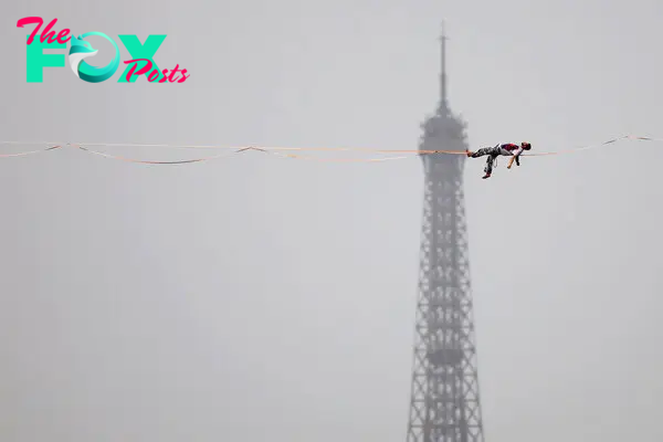 Tightrope walker Nathan Paulin performs on a high rope during the athletes’ parade on the River Seine near the Supreme Court.