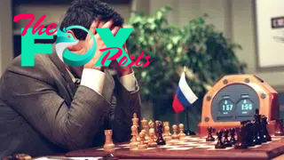 Garry Kasparov holds his head in his hands while sitting at a chessboard