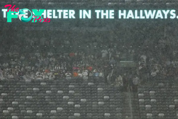 Spectators shelter from rain as the match has been suspended during the pre-season club friendly football match between Real Madrid and FC Barcelona at MetLife Stadium, in East Rutherford, New Jersey on August 3, 2024. (Photo by Charly TRIBALLEAU / AFP)