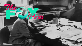 Black and white photograph of Professor Dorothy Mary Hodgkin taken in the 1960s. She is sitting at a large desk overflowing with papers and books.