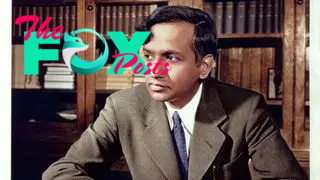 Photo of Subrahmanyan Chandrasekhar sitting at a desk with a bookshelf behind him.