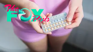 A young woman holds a packet of birth control pills