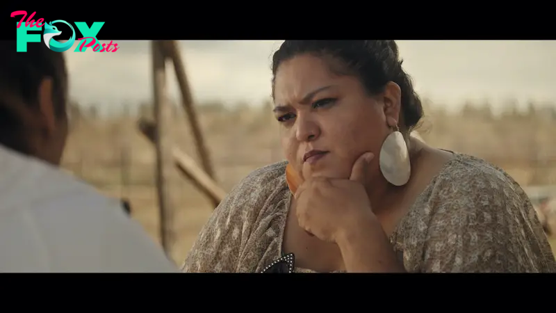 Luella Brien, wearing big dangly shell earrings, looks pensively toward Nakia, sitting just off screen.