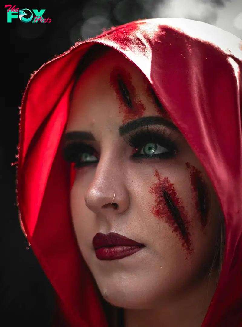 A close-up of a woman with a red hood and a bloody wound on her face | Source: Pexels