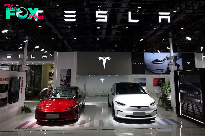 A staff member looks at Tesla's new Model 3 sedan displayed next to Model X SUV at the China International Fair for Trade in Services (CIFTIS) in Beijing, China September 2, 2023. PHOTO: REUTERS