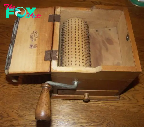 Old wooden box with a grater inside and a crank on the outside.