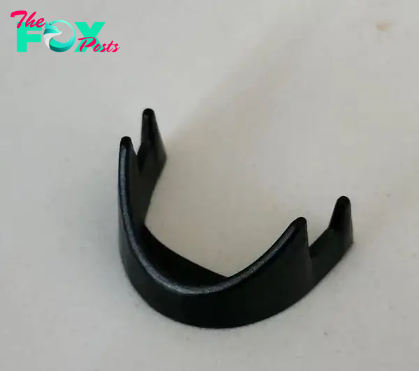 Black plastic mystery item. White background.