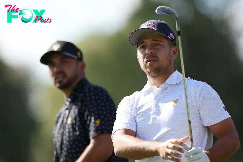 Xander Schauffele of the U.S. Team plays a shot on the eighth hole as Jason Day of Australia and the International Team looks on 