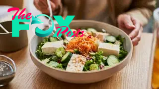 Close up of a bowl of an organic tofu salad being eaten with a fork.