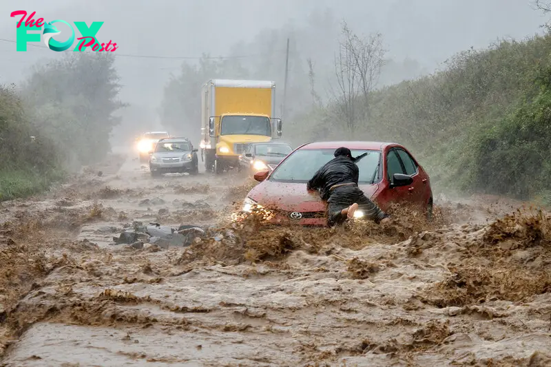 A resident helps free a stranded car as Tropical Storm Helene strikes Boone, North Carolina