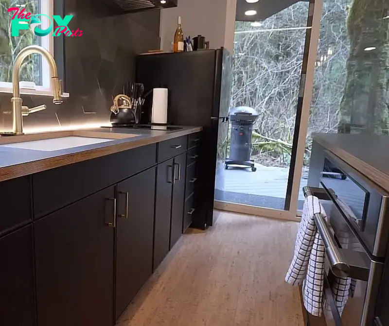 The kitchen at Nick's container home with sink, fridge, oven, and stove.