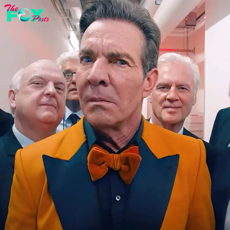 Dennis Quaid, in a bright suit with an orange jacket and bow tie, stands sternly surrounded by eight older men in suits and ties