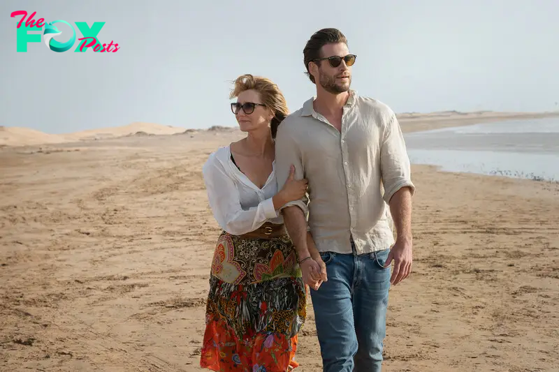 A woman (Laura Dern) and a man (Liam Hemsworth) walking hand-in-hand along a shore in Lonely Planet.