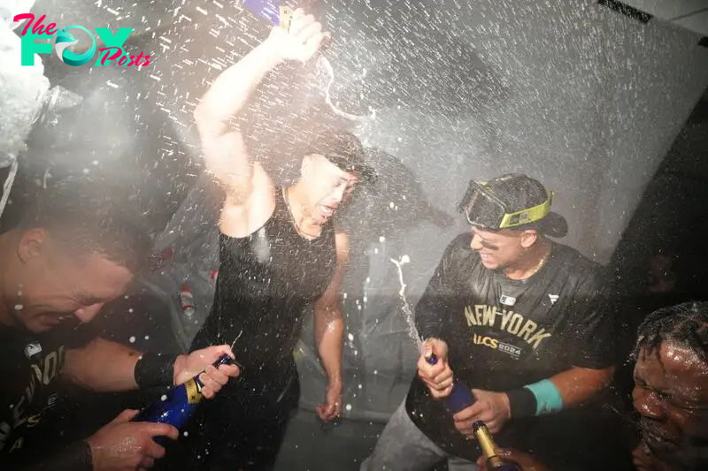 Oct 10, 2024; Kansas City, Missouri, USA; New York Yankees designated hitter Giancarlo Stanton (27), outfielder Aaron Judge (99) and third baseman Jazz Chisholm Jr. (13) spray champagne as the New York Yankees celebrate a win over the Kansas City Royals during game four of the ALDS for the 2024 MLB Playoffs at Kauffman Stadium. Mandatory Credit: Jay Biggerstaff-Imagn Images