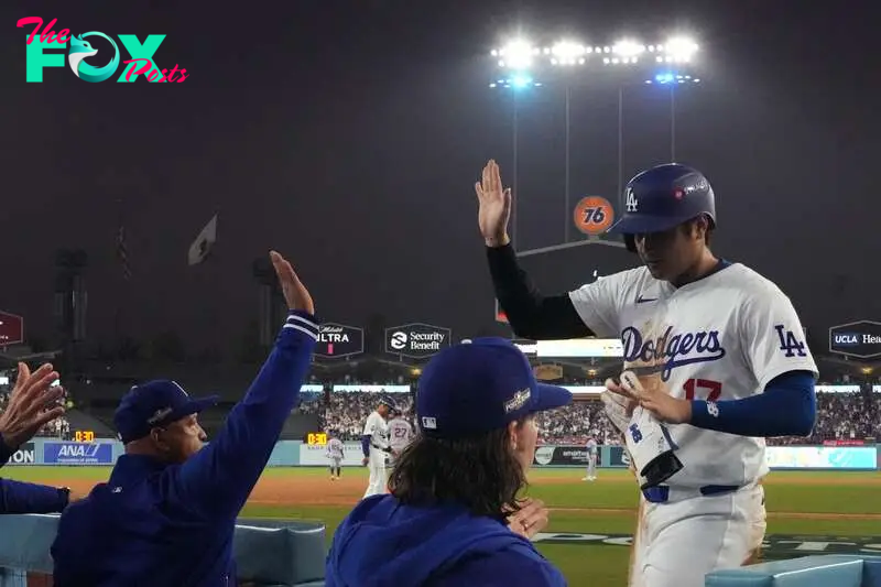 Los Angeles Dodgers Shohei Ohtani (R) high fives Manager Dave Roberts (L) after scoring during the Major League Baseball (MLB) National League Championship Series playoff game one between the New York Mets and the Los Angeles Dodgers in Los Angeles, California