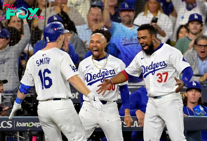 Los Angeles Dodgers catcher Will Smith (16) celebrates with outfielder Mookie Betts (50) and outfielder Teoscar Hernandez 