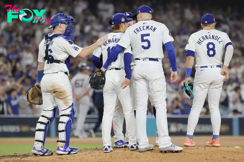 Dodgers pitcher Yoshinobu Yamamoto (C) is greeted by catcher Will Smith (L) and first base Freddie Freeman 