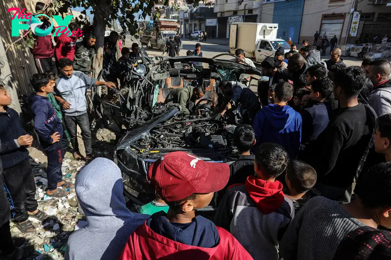 Palestinians look at a wrecked car after two more journalists, who have been identified as Hamza Wael Al-Dahdouh, the son of Al Jazeera Gaza bureau chief Wael Al-Dahdouh, and Mustafa Thuraya, were killed in an Israeli bombing on their car in the city of Khan Younis, Gaza on Jan. 7, 2024.