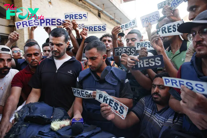 Mourners and colleagues holding 'press' signs surround the body of Al-Jazeera Arabic journalist Ismail al-Ghoul, killed along with his cameraman Rami al-Refee in an Israeli strike during their coverage of Gaza's Al-Shati refugee camp, on July 31, 2024.